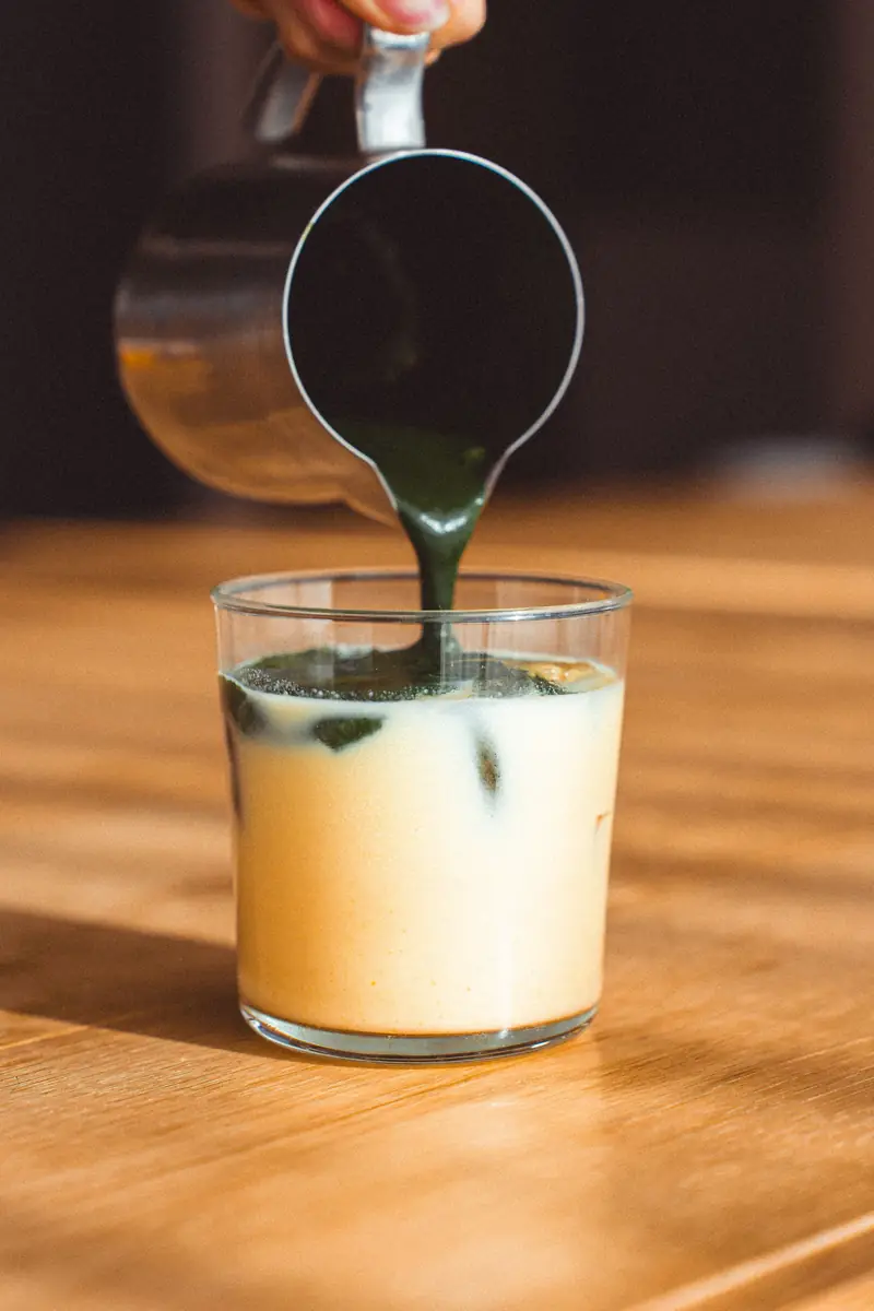 Matcha being poured over iced milk